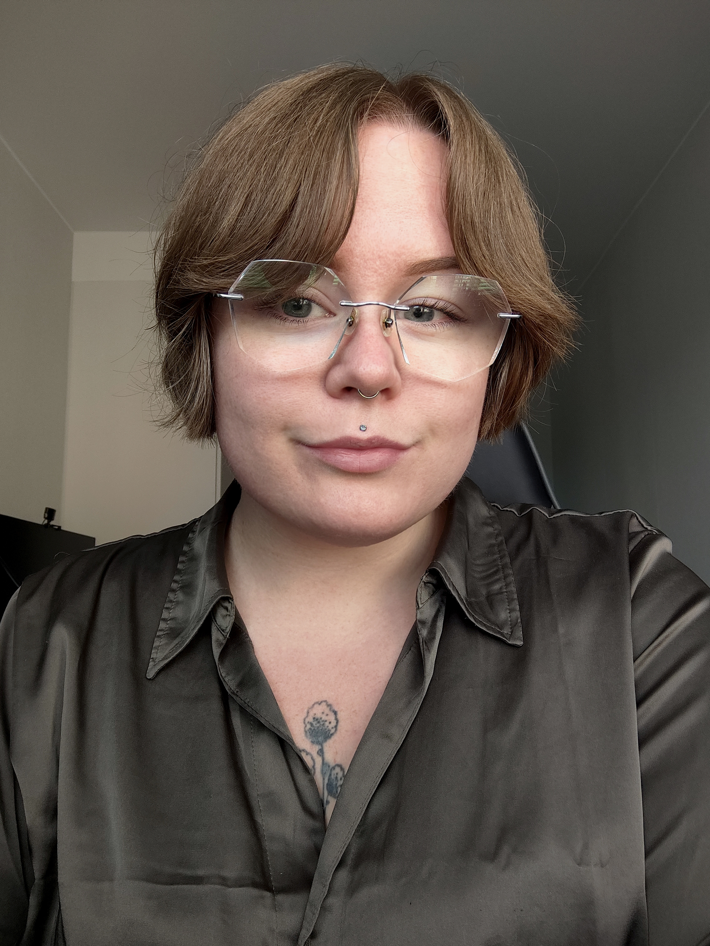 En bild av James. James har kort brunt hår, glasögon och grå skjorta.